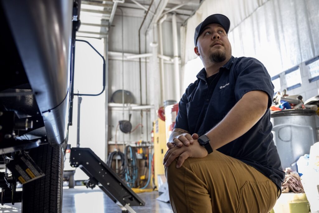 RV tech leaning down by an RV. 