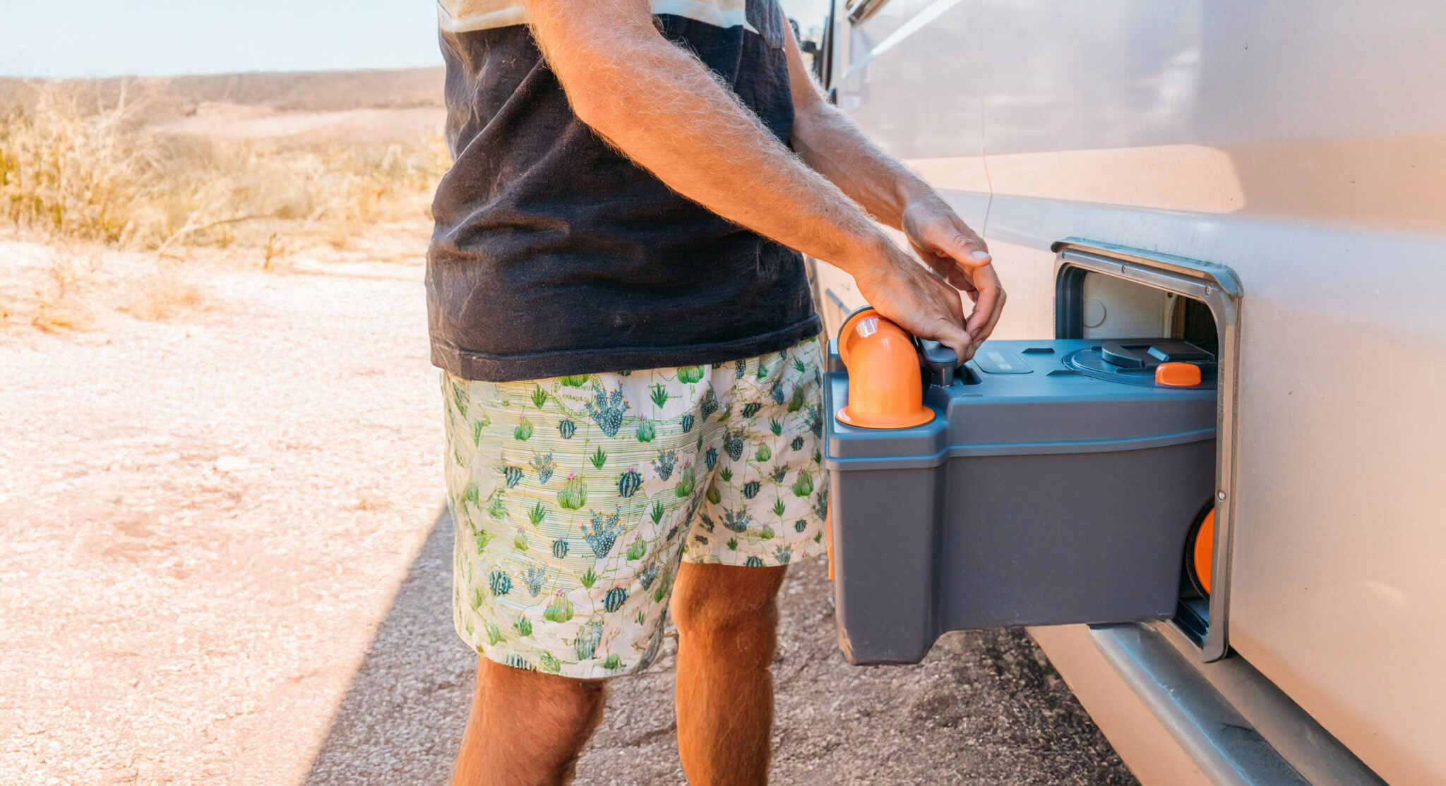 Adult male installing a portable camping toilet into a camper storage