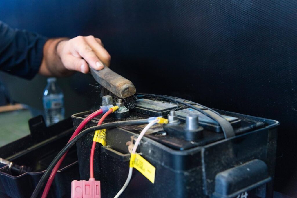 Technician cleaning camper battery terminals