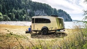 Image of chrome travel trailer by a lake.