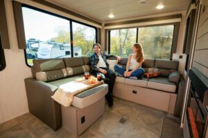 Couple relaxing on L-shaped couch in rear living travel trailer