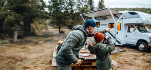 Man pointing out something in the distance as son uses binoculars
