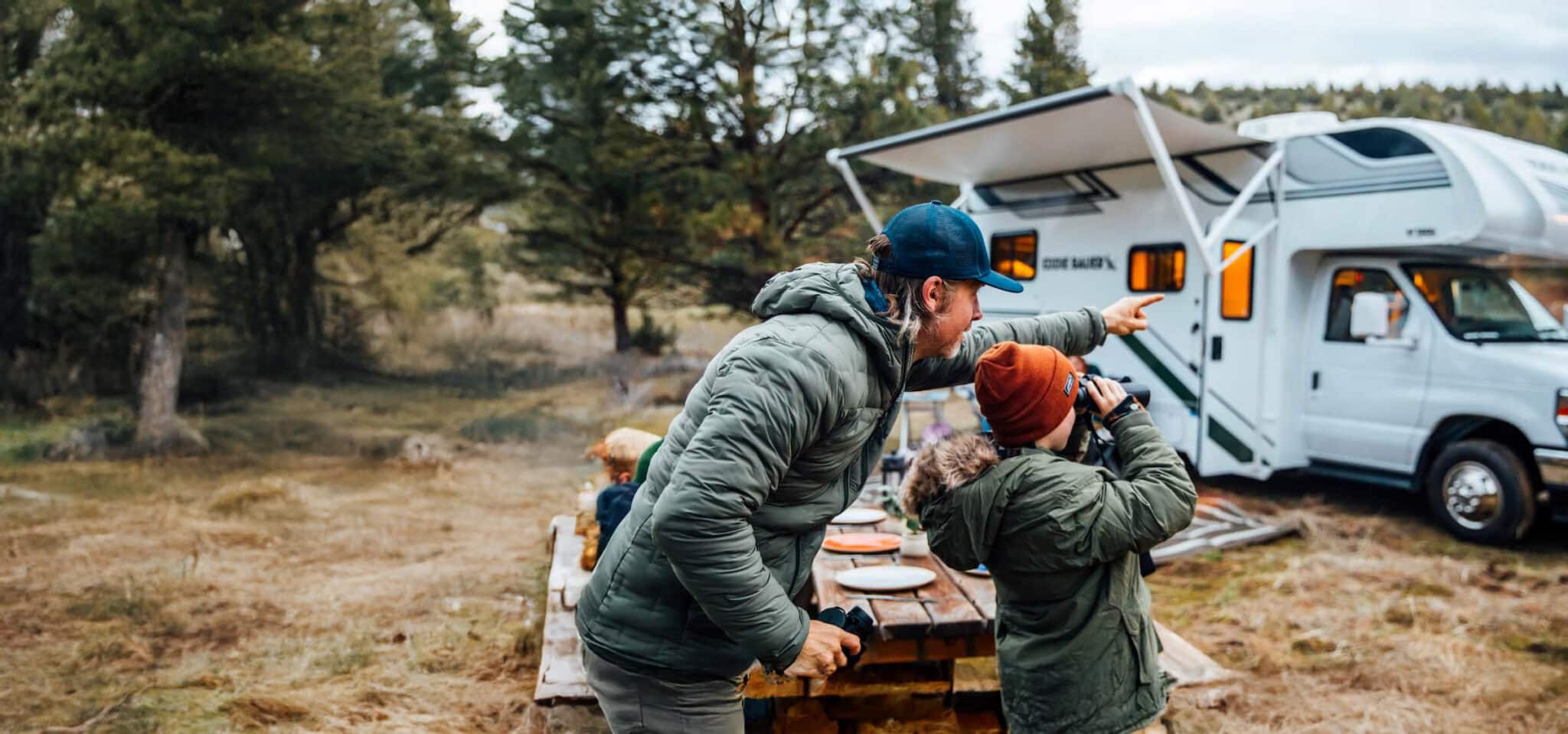 Man pointing out something in the distance as son uses binoculars