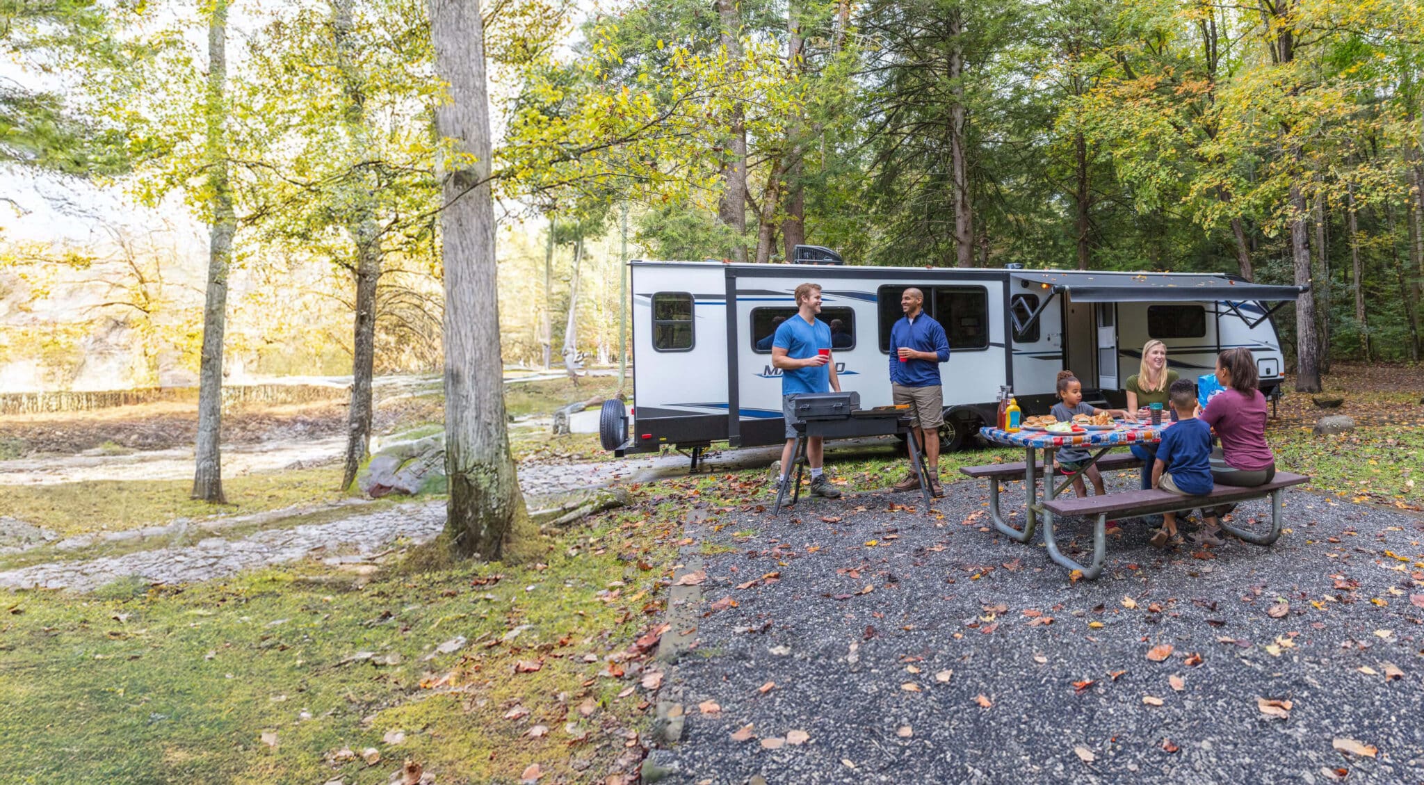 two families grilling outside a travel trailer with 2 queen beds
