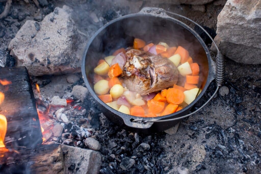 Dutch oven in campfire with lamb and vegetables Image by Daria Nipot via iStock