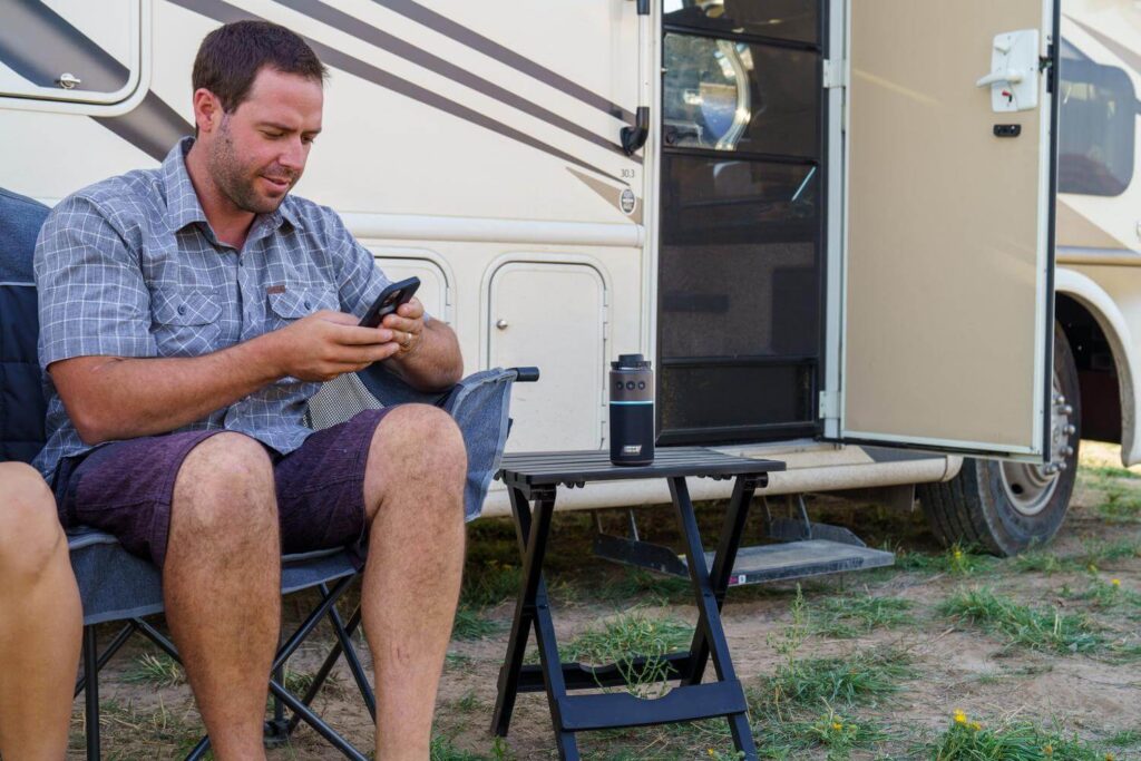Man struggling with cell service outside a camper