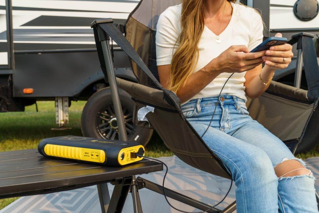 Woman with cell phone plugged into portable power station