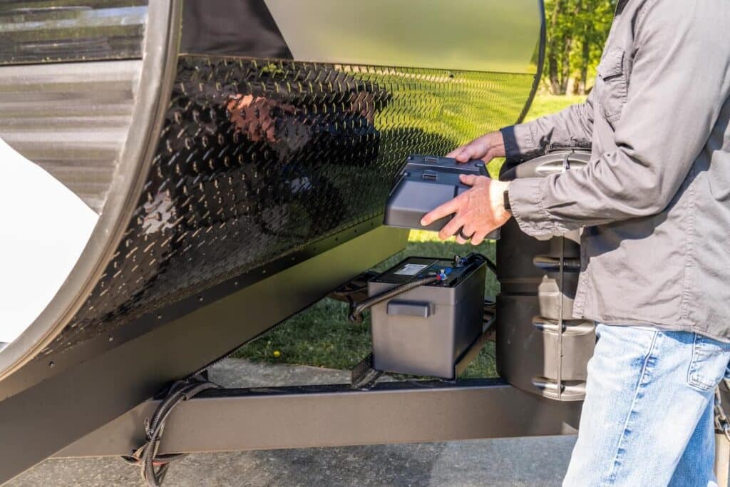 Man putting cover on battery on tongue of travel trailer