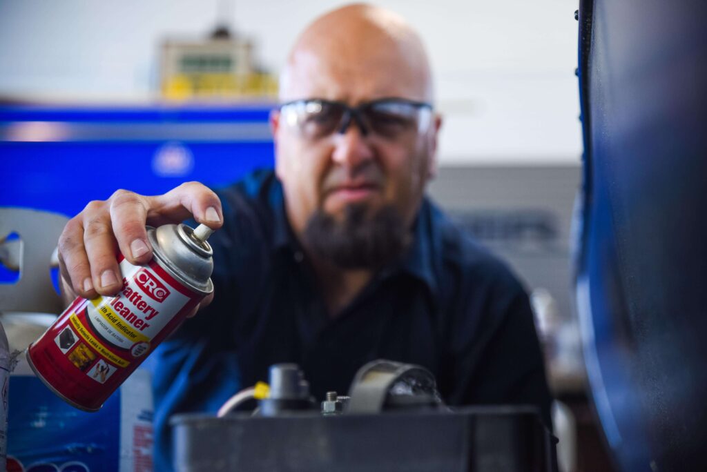 Technician cleaning terminals as part of good RV battery maintenance