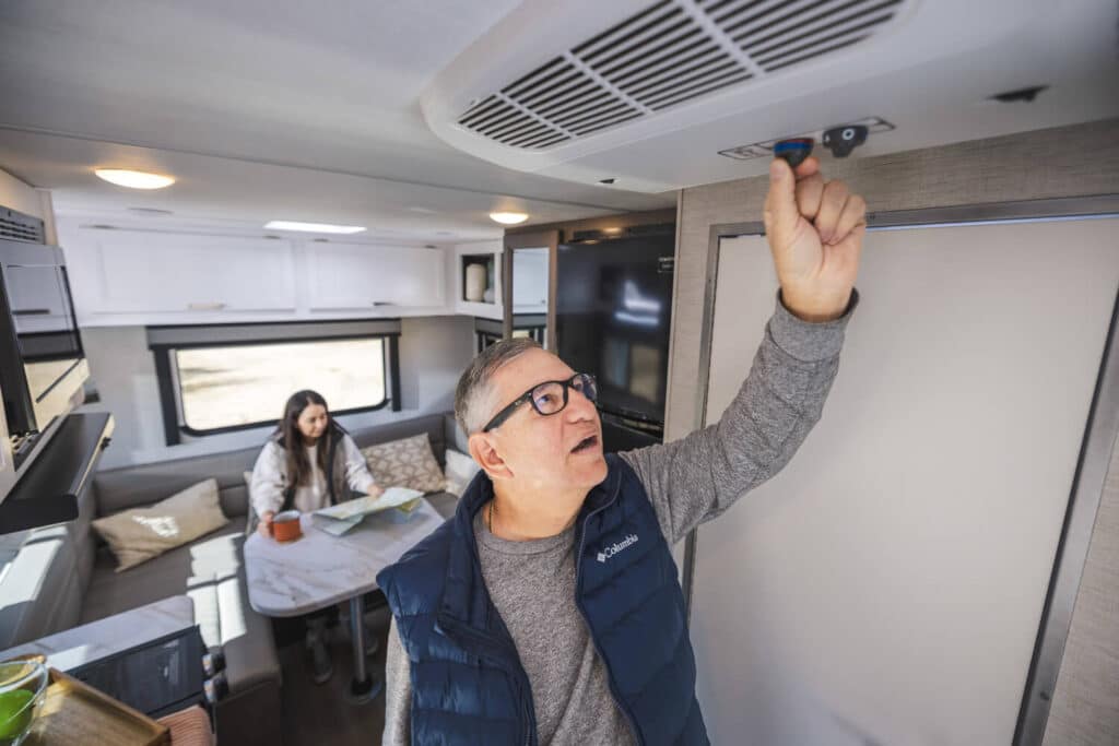 Man turning on inside controls for air conditioner in camper