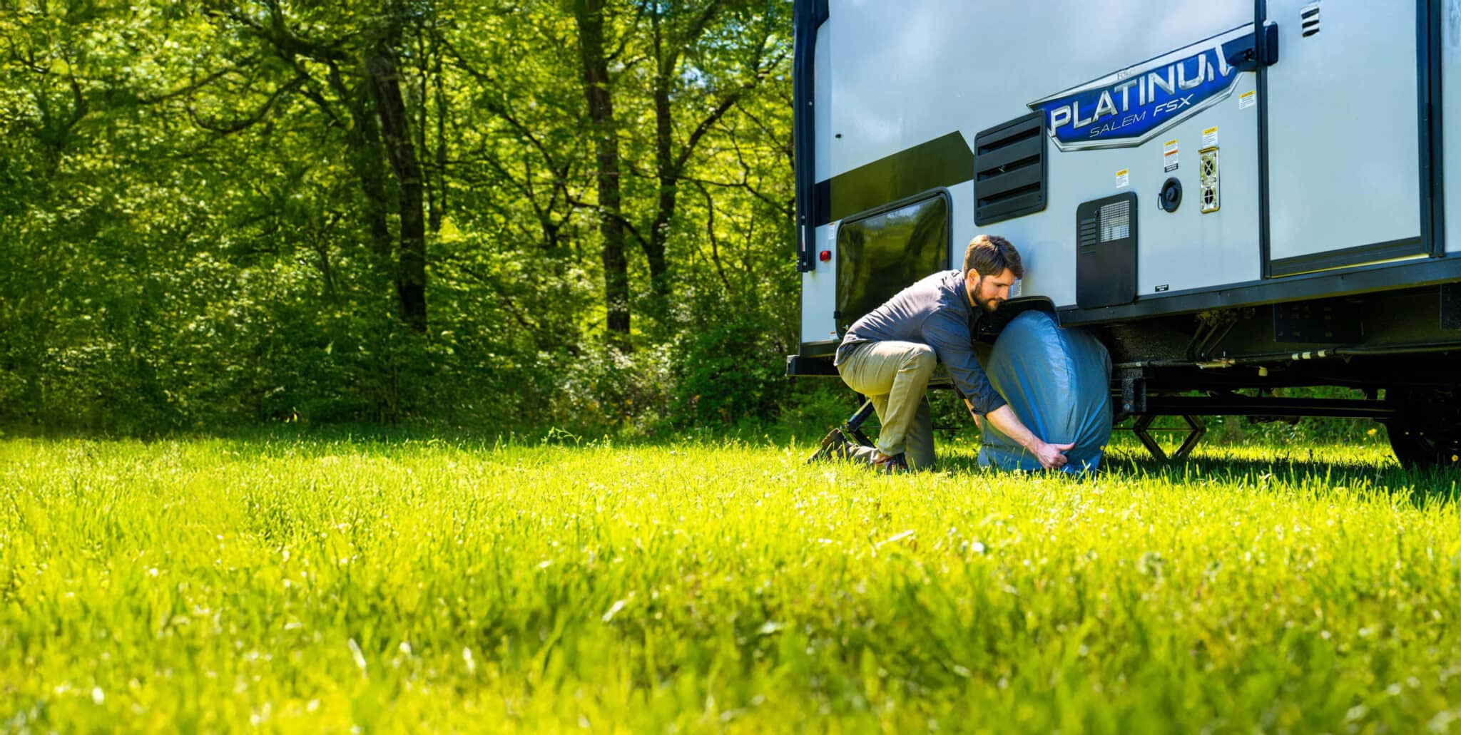 Man installing tire cover on RV travel trailer