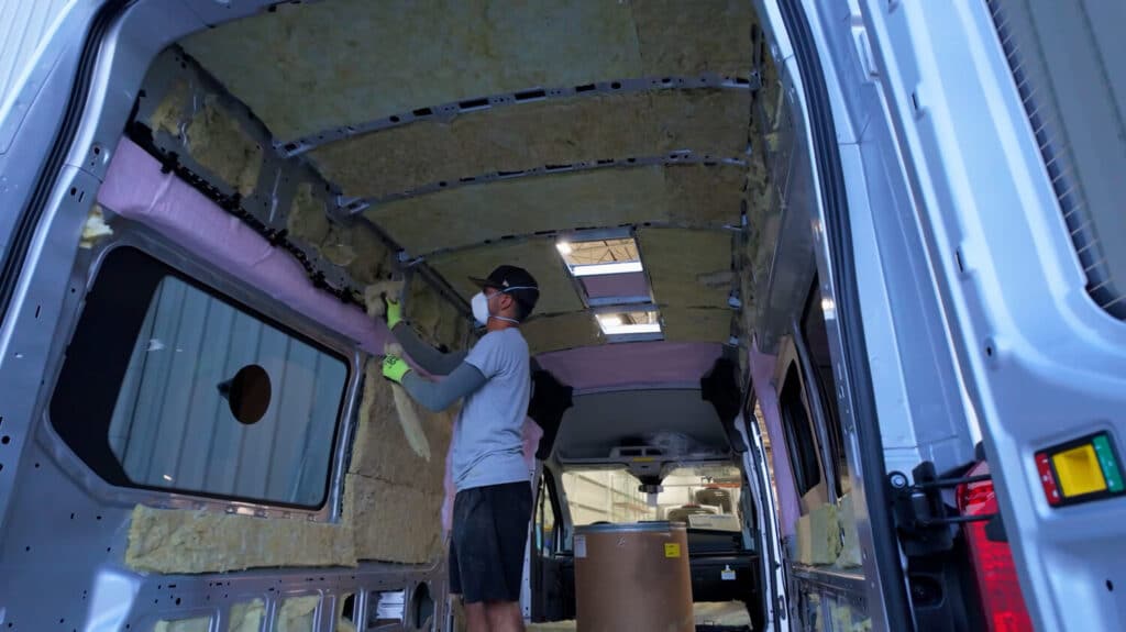Man adding insulation to Class B camper van