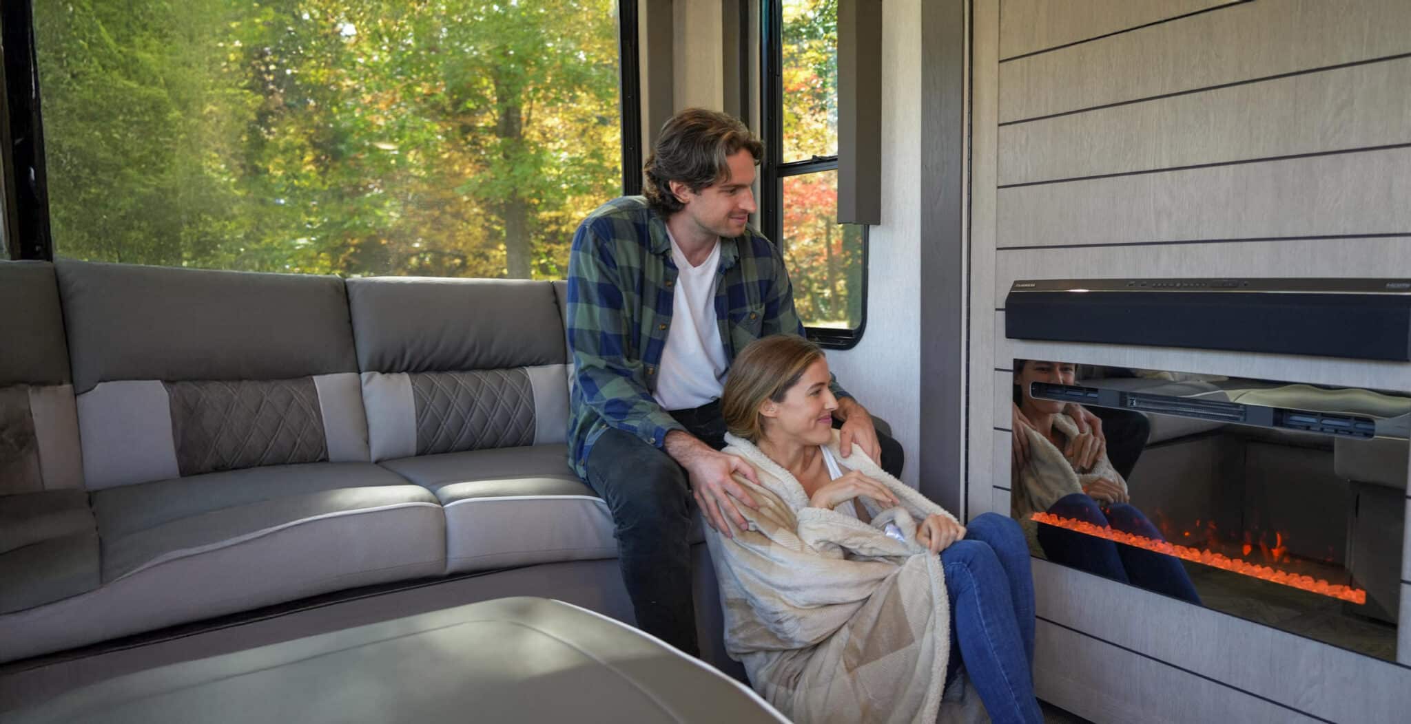 Couple staying warm beside electric fireplace in RV