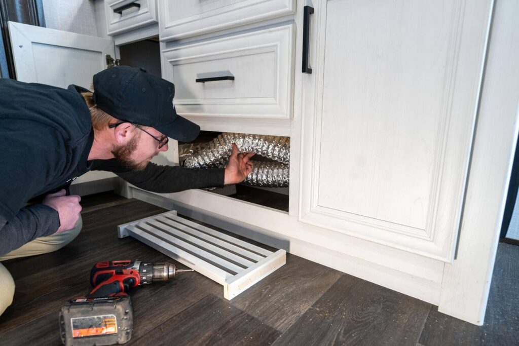 Technician inspecting ductwork for RV furnace replacement inspection