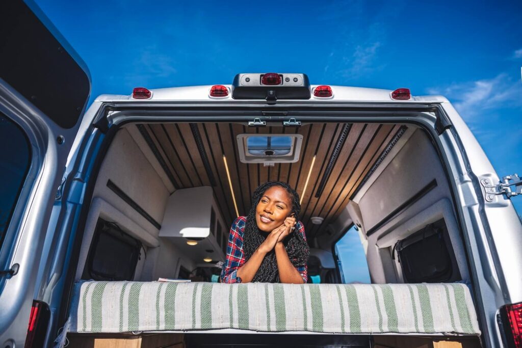 Woman on a bed in the back of a Class B