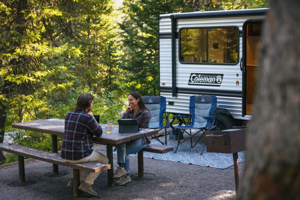 Couple at an RV campsite with woods in the background