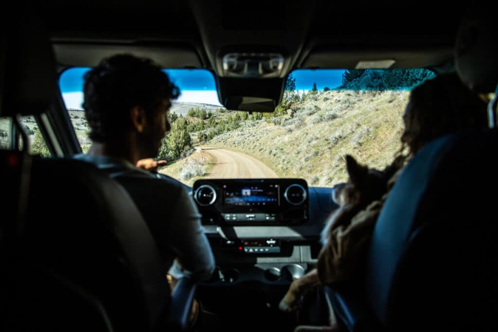 Man and woman driving a motorhome down a dirt road