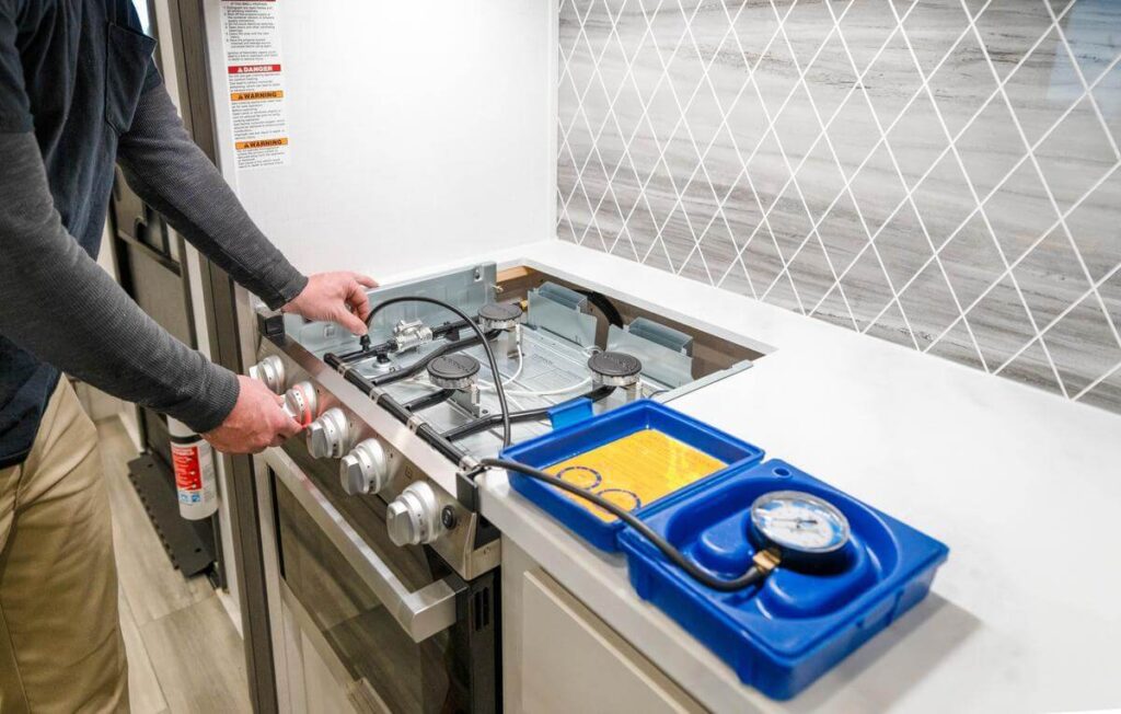 rv technician inspecting gas cooktop