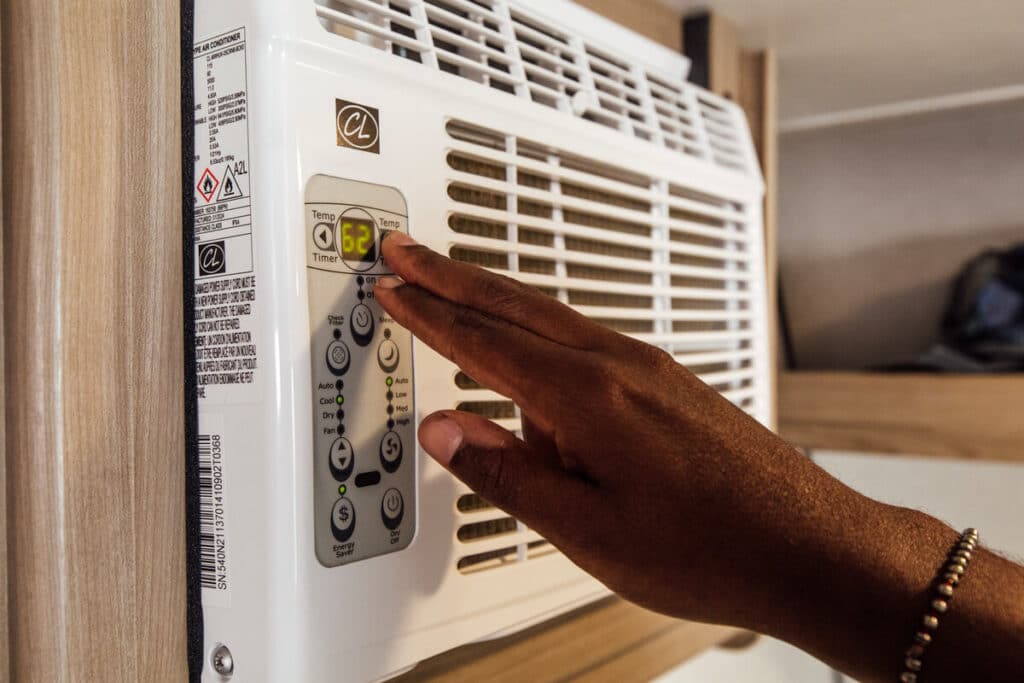 man turning on ac unit for summer rv prep
