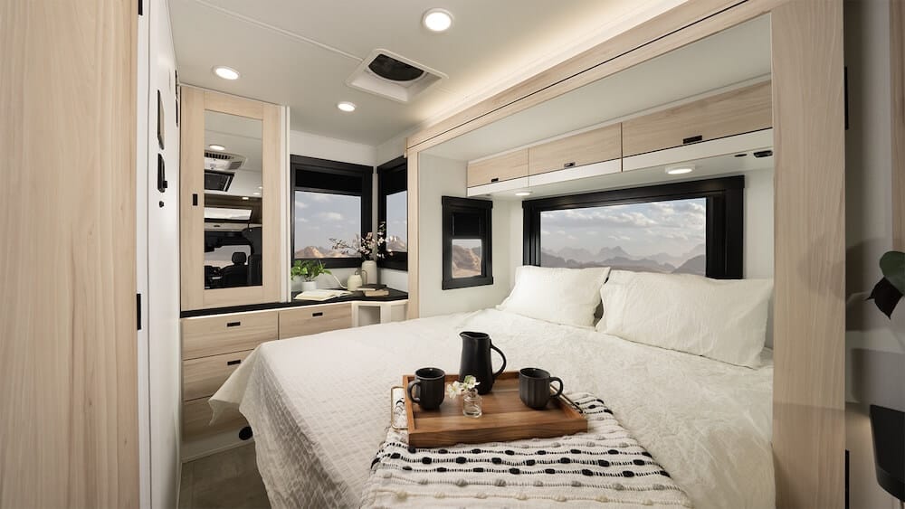 Interior image of the Jayco Melbourne Prestige 25LP Class C RV. It includes the bedroom with bed extended and storage.