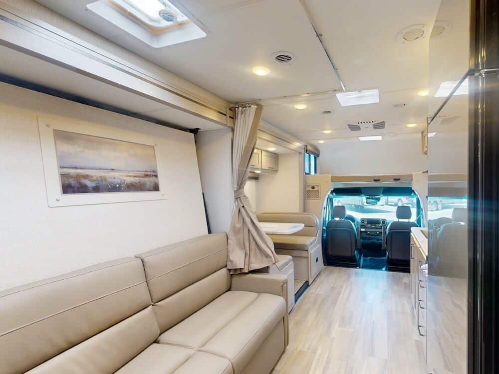 Interior image of the living area for the Thor Coleman 24CL RV. The sofa is to the left and the image faces the cab.