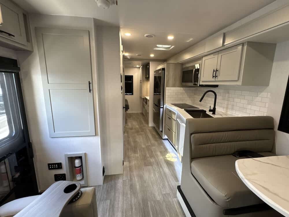 Interior image of the Dynamax Isata 6 31KS. It is facing the rear of the RV and features the dinette and the kitchen.