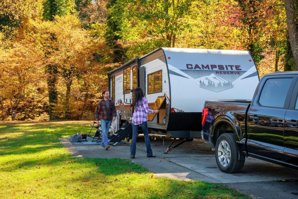 Couple packing up travel trailer after fall camping trip