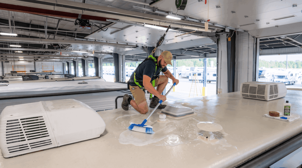 Technician washing camper roof